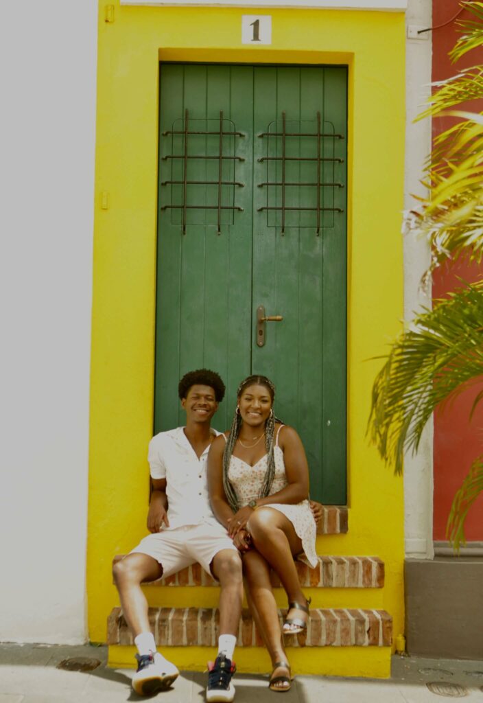 ariel and her husband sitting in front of a colored door